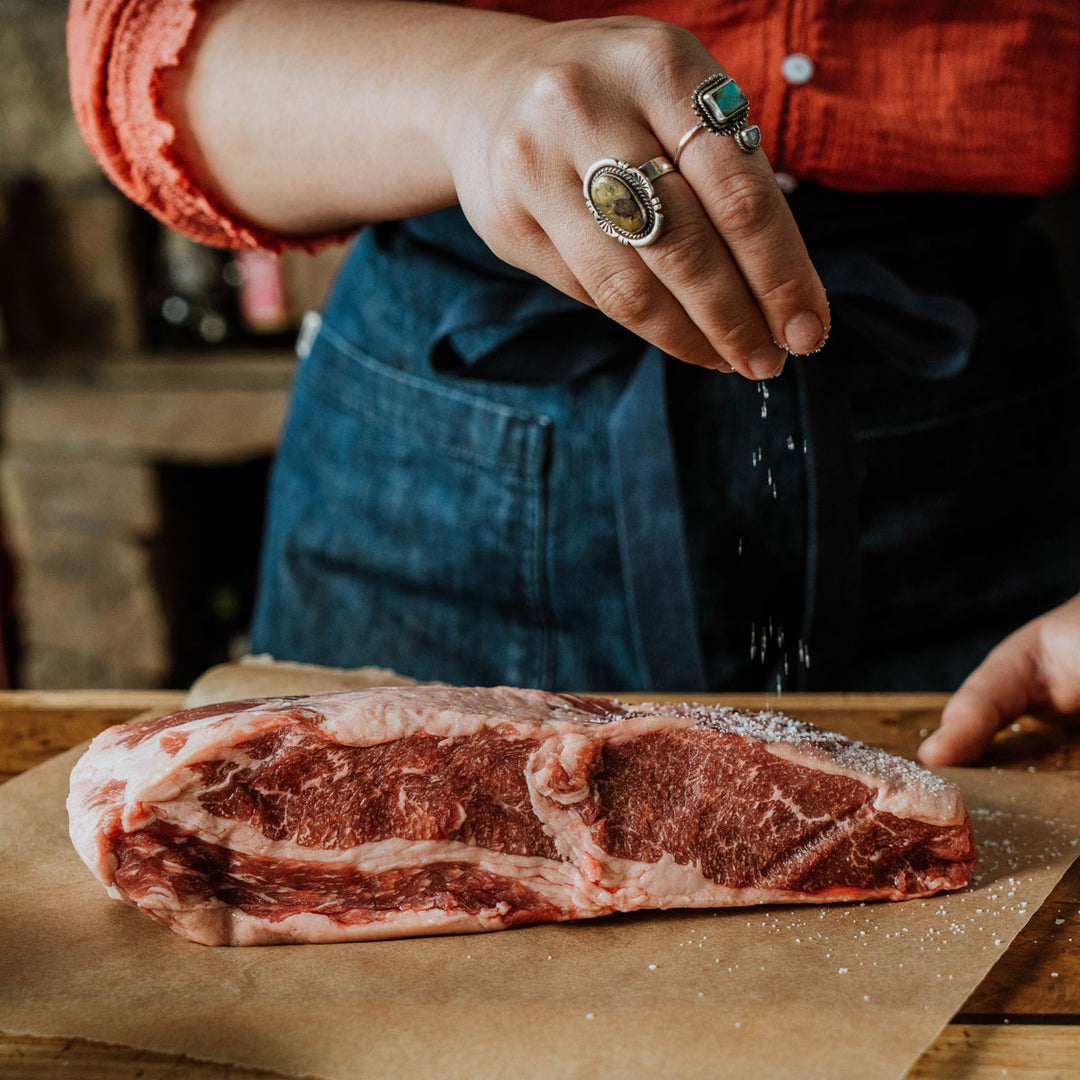 woman salting a raw beef brisket